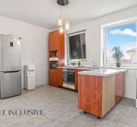 A kitchen with wooden cabinets, a refrigerator, and appliances in a family house.