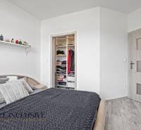 Bedroom with a bed in a family house, open wardrobe, and a shelf with perfumes.