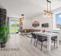 Interior of a family house with a dining table, sofa, and large window.