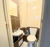 Bathroom with toilet in a 4-room apartment, with a sink and decorative tiles.
