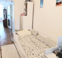 A room in a 4-room apartment with a bed, a shelf, and access to a balcony.