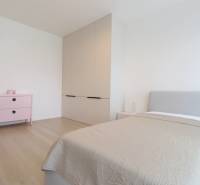 A bright room in a 3-room apartment with a bed, a pink dresser, and a built-in wardrobe.