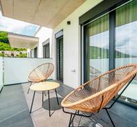 A balcony with rattan chairs and a table in a 3-room apartment, view of greenery.
