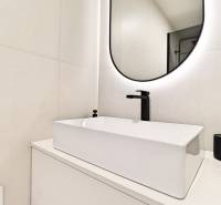 A bathroom in a 3-room apartment with an elegant sink and a backlit mirror.