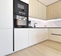 A kitchen with white cabinets and built-in appliances in a 3-room apartment.