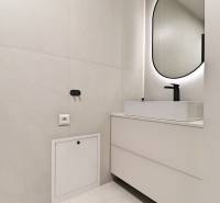 A bathroom in a 3-room apartment with a bright interior and an oval mirror.