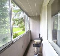 Glazed balcony with a high chair, terrace of a 3-room apartment, view of greenery.