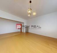 A spacious room with wooden flooring and a light fixture in a 3-room apartment.