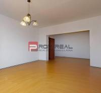 A spacious living room with wooden flooring and a chandelier in a 3-room apartment.