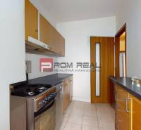 A kitchen in a 3-room apartment with light tiles and wooden cabinets.