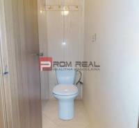 A toilet in a 3-room apartment with light tiles and wooden doors.