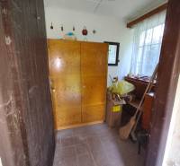 The interior of a cabin with a wooden wardrobe and a window, next to cardboard boxes and a broom.