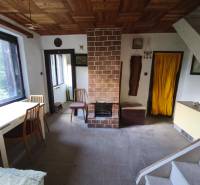 Living space in a cabin with a fireplace, simple furniture, and a floor with a wood decor.