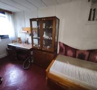 A room with a wooden floor, a wardrobe, a table, and a bed in a cabin.