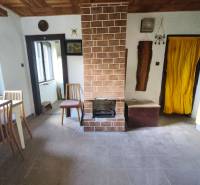 Interior of a cabin with a fireplace, window, and wooden decor flooring.