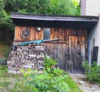 A wooden cabin in the forest at Kordíky in Banská Bystrica with stored wood.
