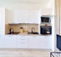 Kitchen in a studio apartment with a white kitchen unit, stove, oven, and open balcony doors.