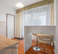 A kitchen in a 2-room apartment with a bar counter, curtains, and light furniture.