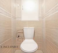 A toilet with beige tiles in a 2-room apartment.