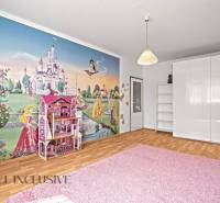 Children's room with fairy tale wallpaper in a 2-room apartment, white furniture and a pink carpet.