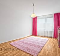 A children's room in a two-room apartment with a pink carpet and curtains.