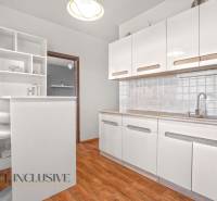 White kitchen with wooden floor and bar counter in a 2-room apartment.