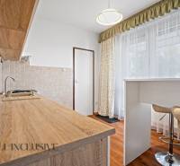 A kitchen in a 2-room apartment with a wooden countertop and high stools.