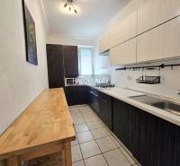 A kitchen with light furniture and a dark countertop in a 3-room apartment.