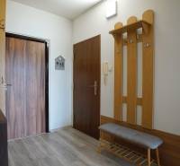 Hallway in a 2-room apartment with a coat rack and wooden doors.