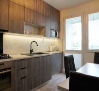 A kitchen with wooden cabinets, a gas stove, and a dining table in a 2-room apartment.