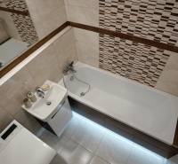 Bathroom in a 2-room apartment with a bathtub, mirror, sink, and washing machine.