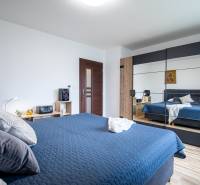 Bedroom with a mirrored wardrobe in a family house, blue bed linen, and wooden decorations.