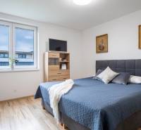 Bedroom in a family house with a double bed, paintings, and a window.