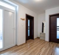 A bright hallway with white walls, wooden doors, and a mirror in a family house.