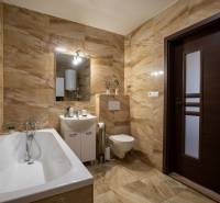 A bathroom in a family house with a bathtub, sink, and toilet in warm tile shades.