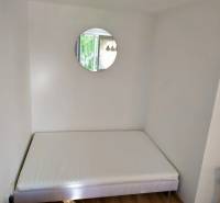 One bed, round mirror, and wooden floor in a studio apartment.