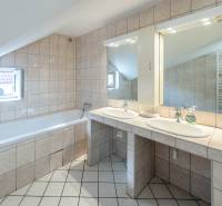 The bathroom in the family house has a bathtub, a double sink, and mirrors with lighting.