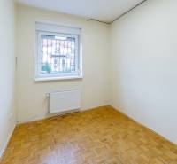 A room with parquet floors and a window in a family house, light walls and a radiator.