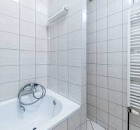 A bathroom in a family house with white tiles and a bathtub.