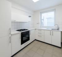 A kitchen in a family house with white cabinets and ceramic flooring.