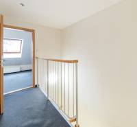 A hallway with wooden railing leads to a bright room, a family house.