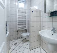 Bathroom with a toilet, sink, and window in a family house. Tiled walls.