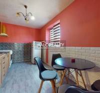 Interior of a 2-room apartment with orange walls, armchairs, and wooden flooring.
