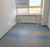 Small office with a large window, blinds, and a radiator, available for rent.