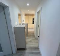 A hallway in a 2-room apartment with wooden flooring and white walls.