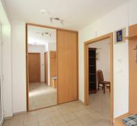 Entrance hallway of a family house with tiles, a mirror, and wooden furniture.