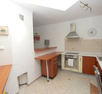 A kitchen in a family house with appliances, a wooden cabinet, and a tiled wall.