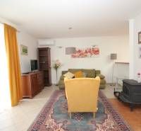 Living room with floral paintings, a yellow armchair, and a green sofa in a family house.
