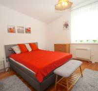 A bedroom in a family house with a gray bed, red blankets, and wooden furniture.