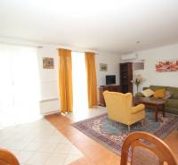 Living room in a family house with a sofa set and an armchair, decorated with paintings and curtains.